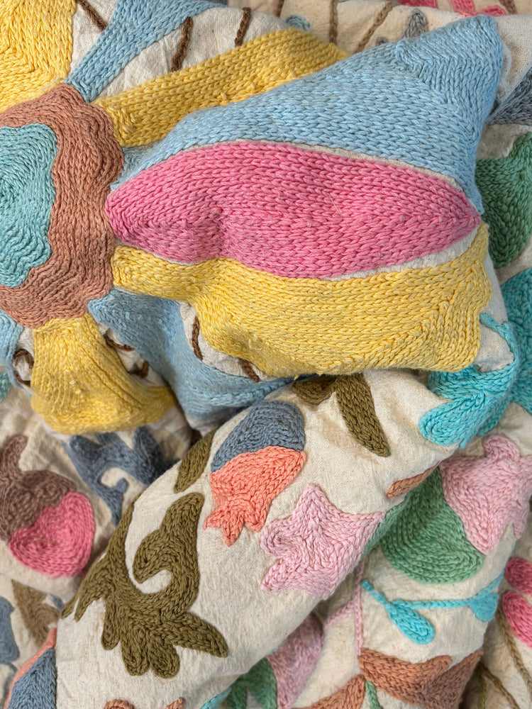 Colorful knitted and embroidered cushions on a textured fabric background