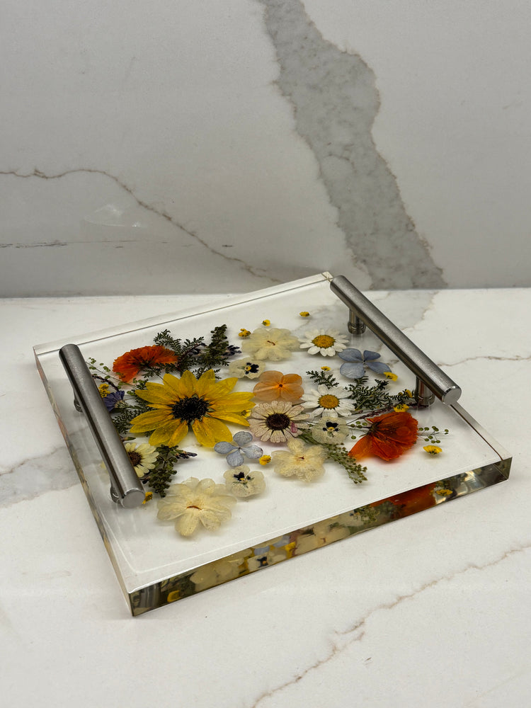 Square clear resin tray featuring a beautiful arrangement of embedded dried yellow and red flowers with metallic accent handles.