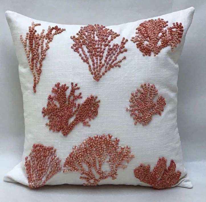 A square-shaped decorative pillow with an embroidered applique of knotty coral in natural tones, primarily in red and white colors on a natural beige background.