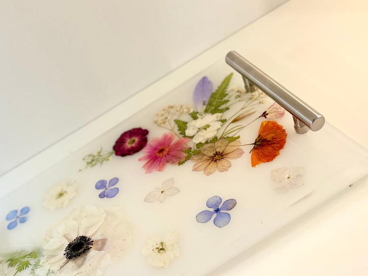 Decorative drawer with pressed flowers and a silver metallic handle on a white surface.