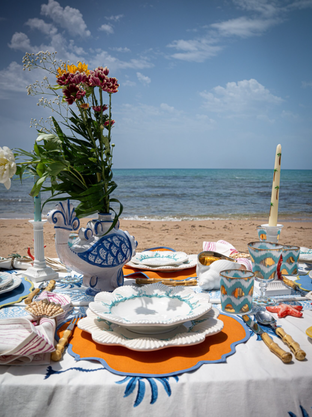 Table setting with decorative plates and flowers on a beach