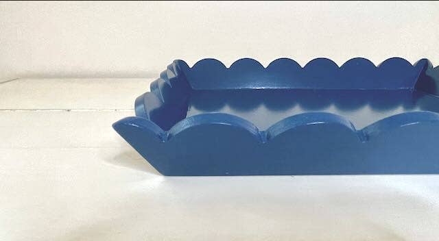 A rectangular blue wooden tray with scallop details on the edges, placed against a white background.