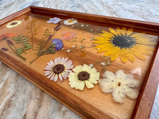 Wooden tray with pressed flowers on a marble surface