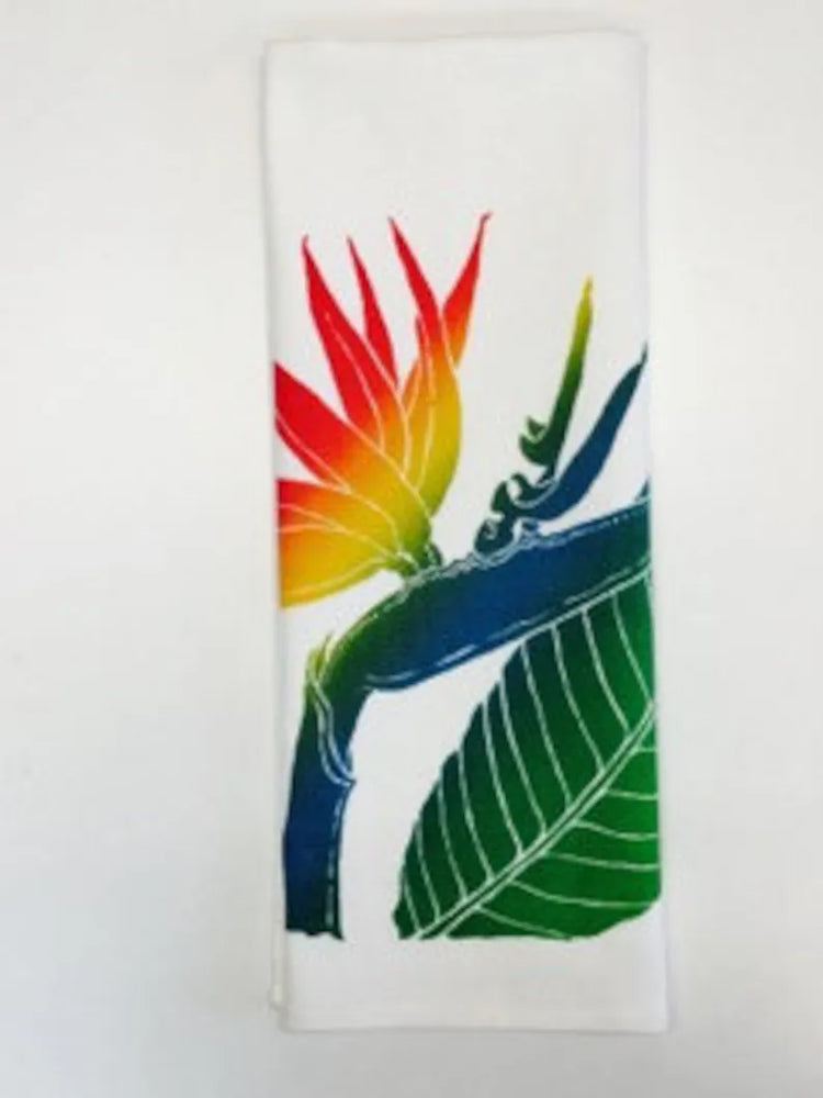 A colorful kitchen towel featuring a hand-screened tropical Bird of Paradise design with green leaves and a multicolored flower.