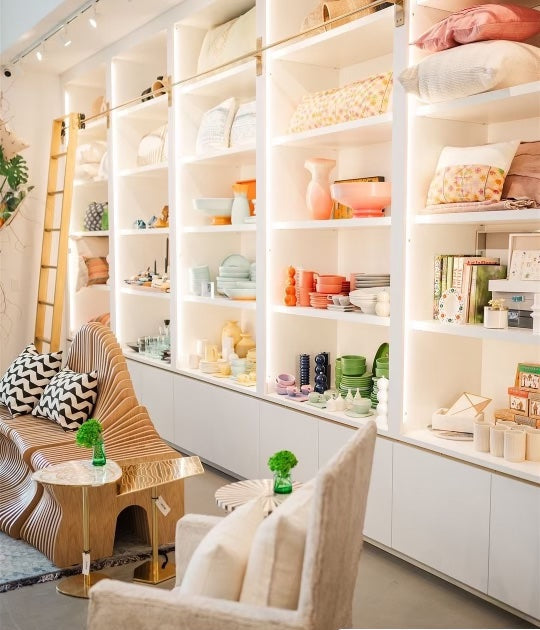Modern interior with white shelves displaying decorative items, a chair, and a small table.